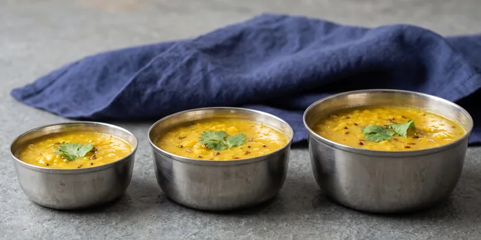 Three steel katoris of dal tadka in a row: small, medium and large.